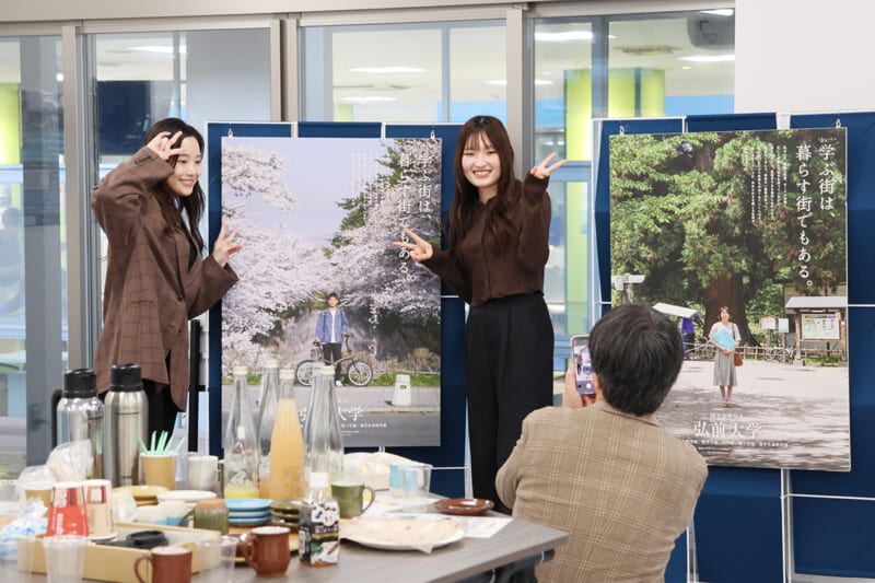 大学イメージポスターを背景に記念写真