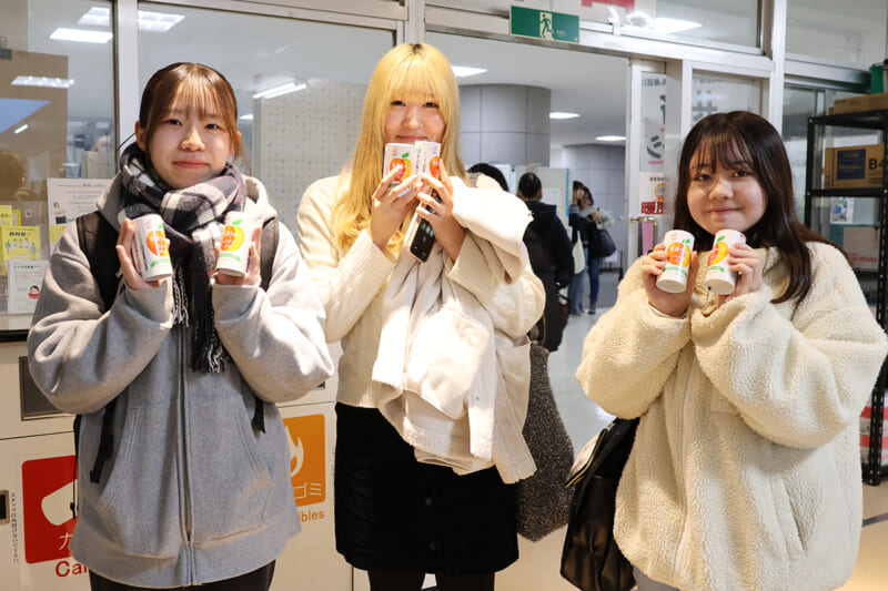 リンゴジュースを手にして笑顔の学生たち(文京町キャンパス)