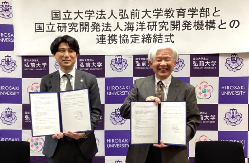 協定書を手にする工藤理事と長南教育学部長