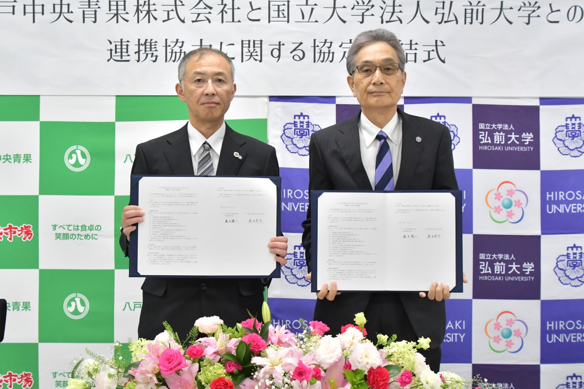 協定書を手にする春日社長と福田学長